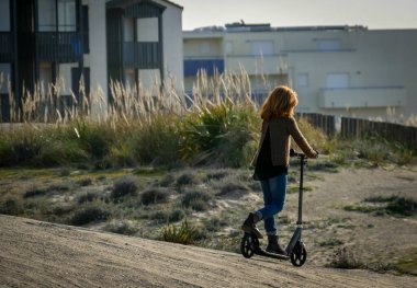 Şapkalı, eldivenli ve bileklikli bir kız dışarıda mobiletle kayıyor.