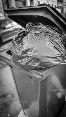 Çöplerle dolu koyu gri çöp kutusu ve plastik torba siyah ve beyaz stil.