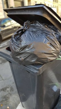 Koyu gri çöp kutusu çöp ve plastik torbayla dolu.