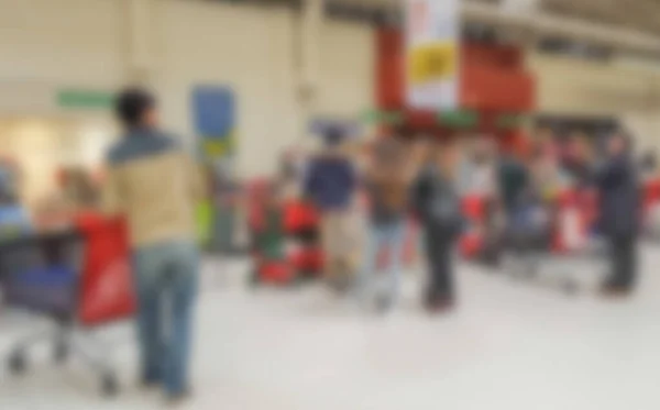 Abstract blurred background : People are shopping in supermarket,  customers are waiting with their carts at counters for checkout payment with the cashiers. Shopping, customers concept