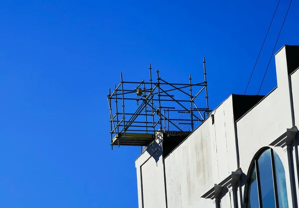 Стяжка і підйомна шкірка на вершині будівлі в будівельній зоні на тлі блакитного неба — стокове фото