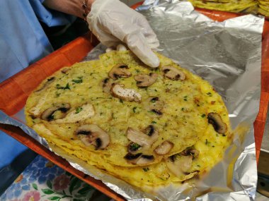 Bir kadın, Banh Xeo adında pirinç unu, su ve zerdeçal tozundan yapılmış vejetaryen Vietnam usulü kızarmış krep yapıyor.