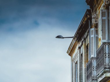 Fransa 'nın güneyinde tipik dar balkonu ve pencereleri olan eski bir bina, açık gökyüzüne ve sokak ışığına karşı..