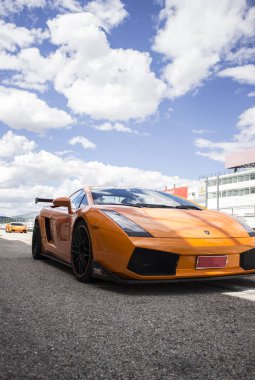 Turuncu Lamborghini lüks araba güneşli bir yaz gününde yarış pistinde koşmaya hazır.