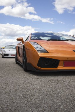 Turuncu Lamborghini lüks araba güneşli bir yaz gününde yarış pistinde koşmaya hazır.