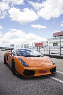 Turuncu Lamborghini lüks araba güneşli bir yaz gününde yarış pistinde koşmaya hazır.