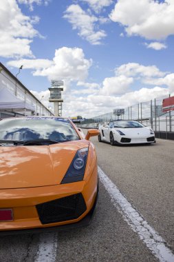Turuncu Lamborghini lüks araba güneşli bir yaz gününde yarış pistinde koşmaya hazır.
