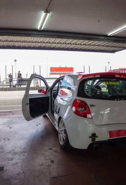 Bir yarış pistinin garajındaki beyaz araba koşmak için tamir edildi.