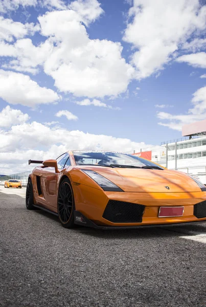Turuncu Lamborghini lüks araba güneşli bir yaz gününde yarış pistinde koşmaya hazır.