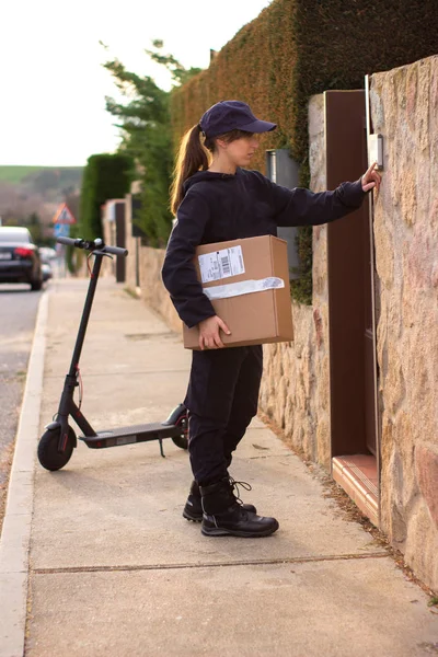 Elektrikli scooterlı genç bir kuryenin eve teslim etmesi gereken bir karton kutusu var.