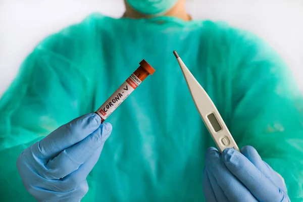 Doctor holds a thermometer and a test tube with blood to examine the virus crown in a hospital