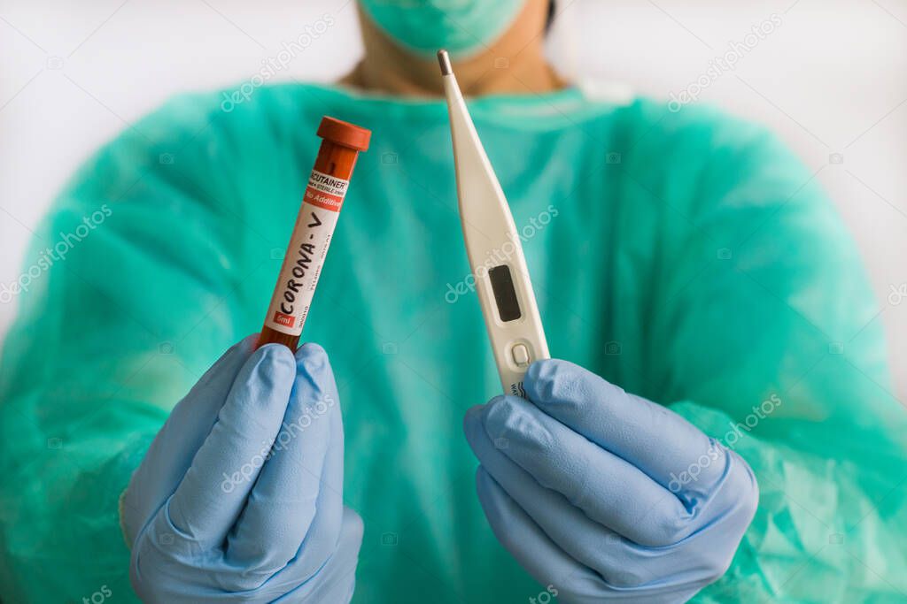 Doctor holds a thermometer and a test tube with blood to examine the virus crown in a hospital