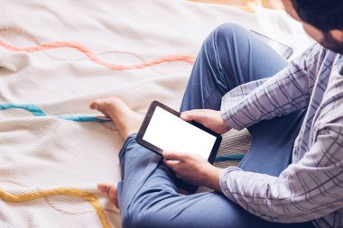 Çocuk tablet ve müzik kulaklıklarıyla yerde oturuyor.