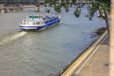 Paris 'teki Seine Nehri' nde insanlarla birlikte yürüyen bir tekne, Avrupa 'da yaz tatili. Aşk ve aşıklar şehrinde turistler nehir boyunca yürür.