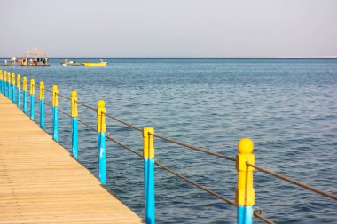 Deniz kıyısında çitleri olan tahta köprü, yaz tatili ve deniz kenarında dinlenme.