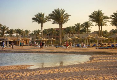 Lüks tatil köyü: güneşten korunmak için sahil ve saman şemsiyeler, deniz kenarında tembel yaz tatili, güneşli güzel bir gün..