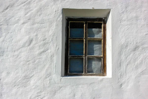 Ett gammalt fönster mot bakgrunden av ett vitt lerhus i byn på sommaren. — Stockfoto