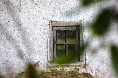 Köydeki beyaz bir evde eski, kırık bir pencere çerçevesi.
