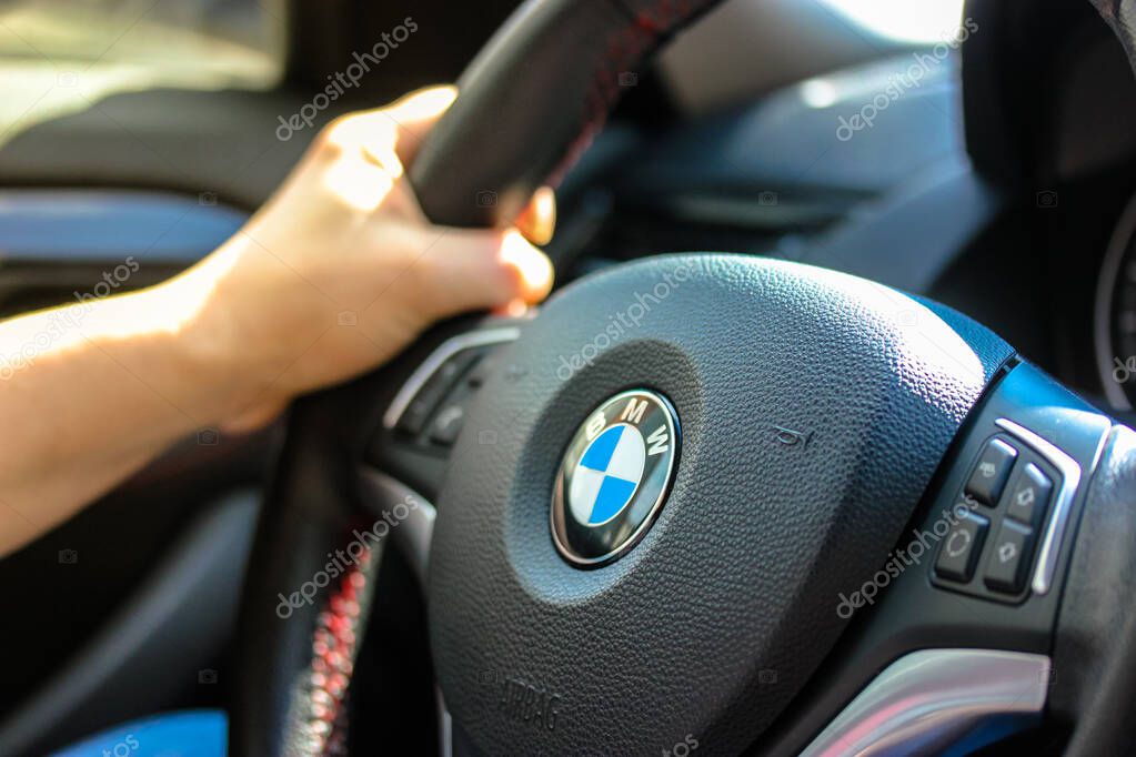 A person sitting in a car and handles the wheel: BMW logo