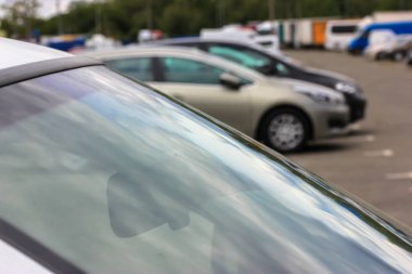 Arabanın ön camı ve arka plandaki bulanık arabalar: büyük şehirdeki park yeri veya büyük otopark
