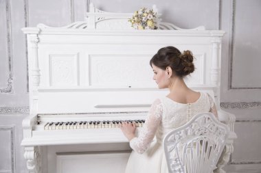 geriye doğru oturma ve piyano beyaz gelinlik içinde genç gelin 