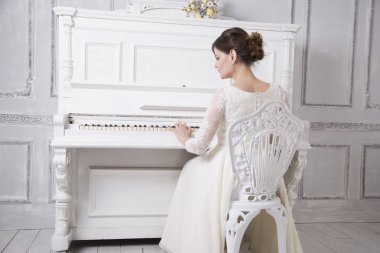 geriye doğru oturma ve piyano beyaz gelinlik içinde genç gelin 