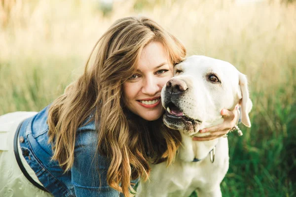 Beyaz bir labrador köpek güzel bir kızla çalış ve yüzünü yalıyor
