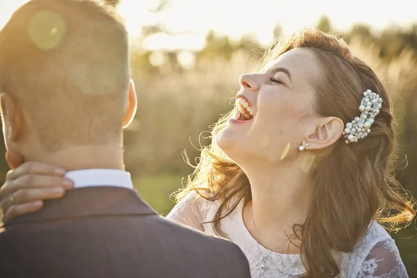Een jonge bruid lacht en schreeuwt in het oor van de bruidegom — Stockfoto