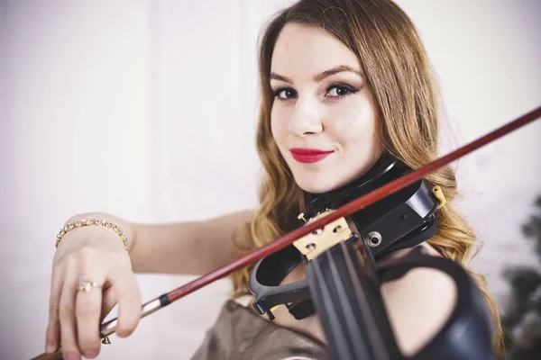 Uma menina bonita com lábios vermelhos toca um violino elétrico. Close-up. Retrato . — Fotografia de Stock