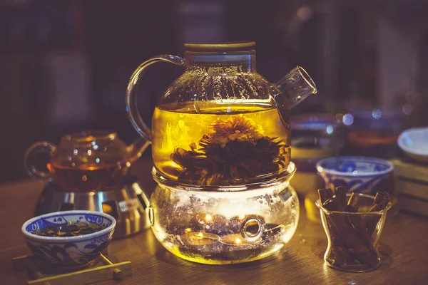 Цветущий цветочный чай в стеклянном чайнике с традиционными китайскими аксессуарами. Toned — стоковое фото