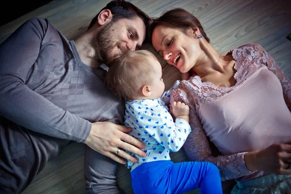 Padres jóvenes con su hijita en el suelo. Concepto de familia feliz —  Fotos de Stock