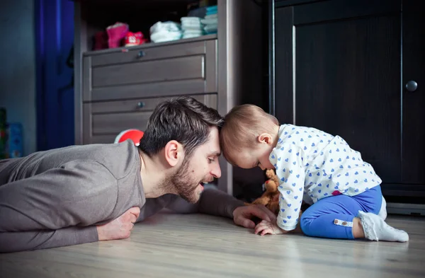 Genç baba küçük kızı ile odasında yerde oynuyor. Mutlu bir aile kavramı
