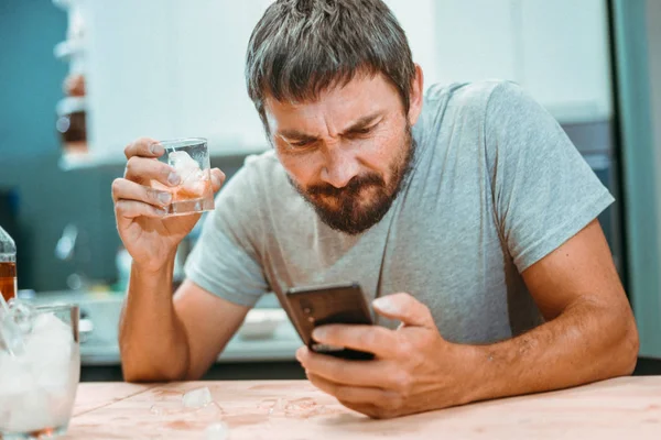 Homem bêbado com barba olha para a tela de um telefone celular Imagens Royalty-Free