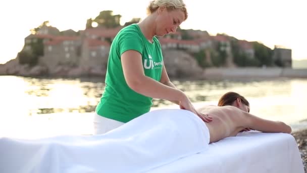 Mujer relajante masaje de espalda en la playa en la mesa de masaje. Mujer joven que tiene masaje en el spa. Cierre — Vídeo de stock