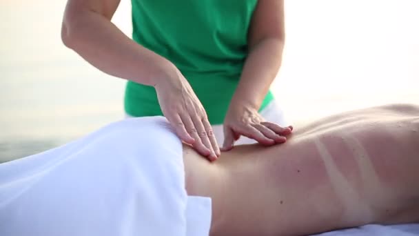 Frau entspannende Rückenmassage am Strand auf Massagetisch. Junge Frau bei einer Massage im Wellnessbereich. Nahaufnahme — Stockvideo