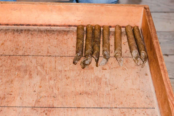 Rolo de charuto, folha de tabaco e charuto em uma mesa — Fotografia de Stock