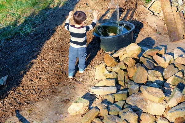 Little child throwing pebbles into the water — Stock Photo, Image