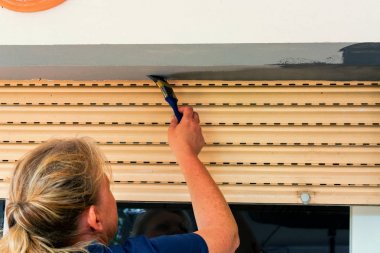 Pencere çerçevesini fırçalayan bir kadının arka planı.