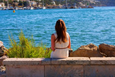 Harbor bir duvara oturan genç kadın      