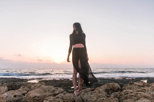 Gün batımında havuz kenarında yürüyen genç ve güzel bir kadın. 