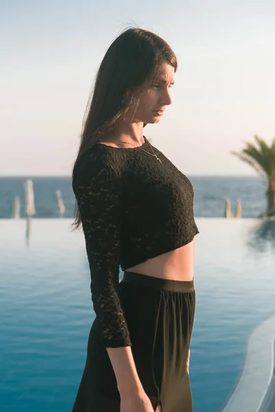 Gün batımında havuz kenarında yürüyen genç ve güzel bir kadın.