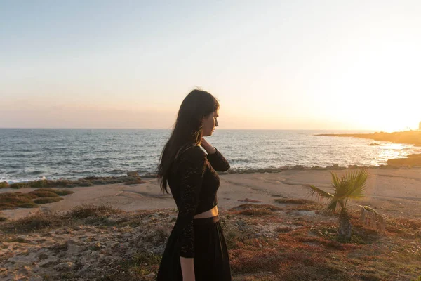 Genç moda güzeli kadın gün batımında sahilde yürüyor.