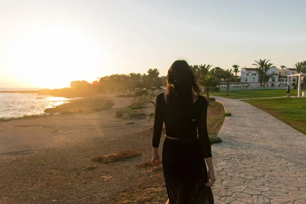 Genç moda güzeli kadın gün batımında sahilde yürüyor.