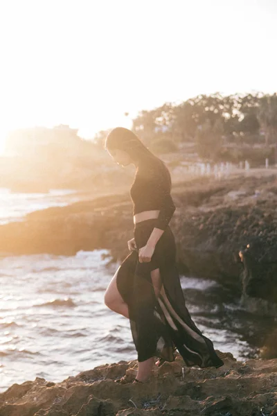 Genç moda güzeli kadın gün batımında sahilde yürüyor.