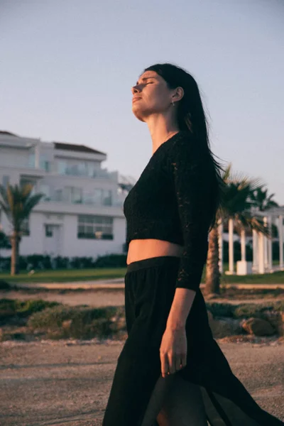 Genç moda güzeli kadın gün batımında sahilde yürüyor.