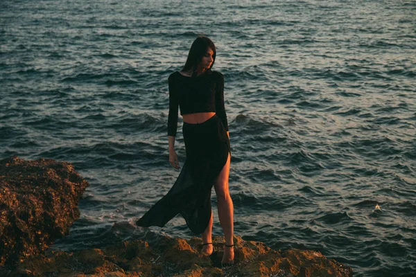 Genç moda güzeli kadın gün batımında sahilde yürüyor.