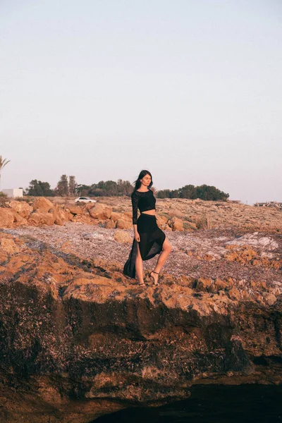 Genç moda güzeli kadın gün batımında sahilde yürüyor.