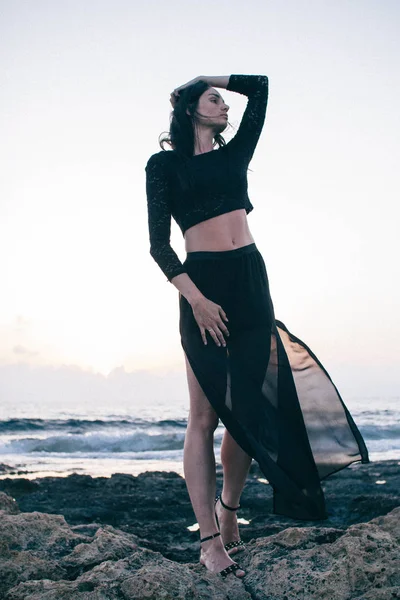 Gün batımında sahilde yürüyen genç ve güzel bir kadın.