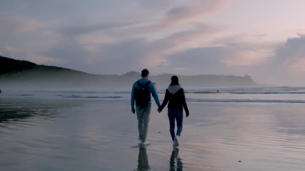 Tofino Vancouver Island, vue aérienne sur la plage de Tofino avec des personnes surfant pendant le coucher du soleil Vancouver Island Canada, couple marchant sur la plage — Video