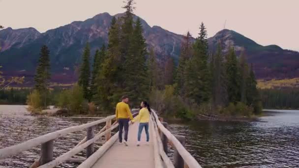 Пара у озера наблюдая закат, Пирамида озера Джаспер в течение осени в Альберте Канада, падать цвета на озере во время заката, Пирамида острова Джаспер — стоковое видео